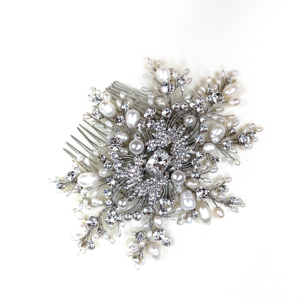 bridal hair comb with large crystal in the middle, surrounded by silver detailing and sprigs of crystal and pearl