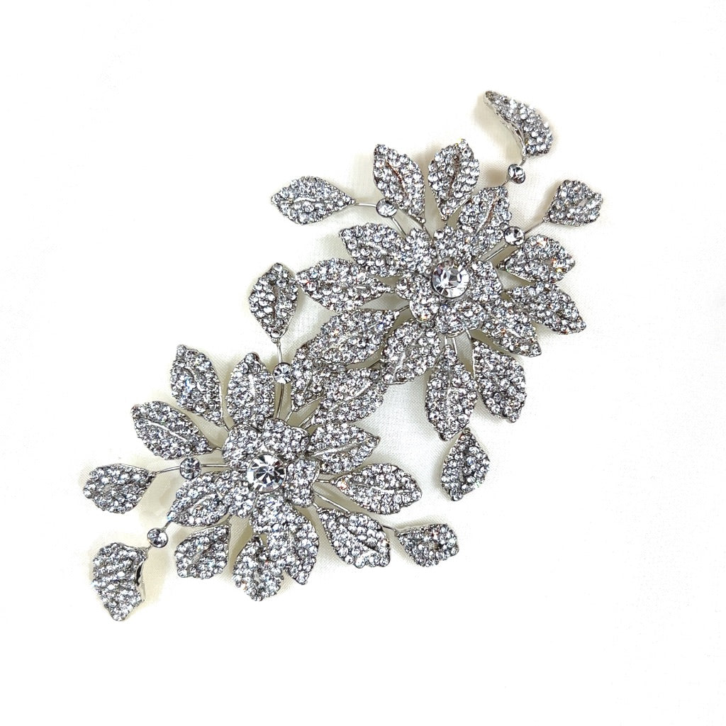 The Dazzling Double Blossom Bridal Hair Comb, style no. 80065, features two ornate and sparkling brooches with large flower designs made of intricately arranged Swarovski crystals. 