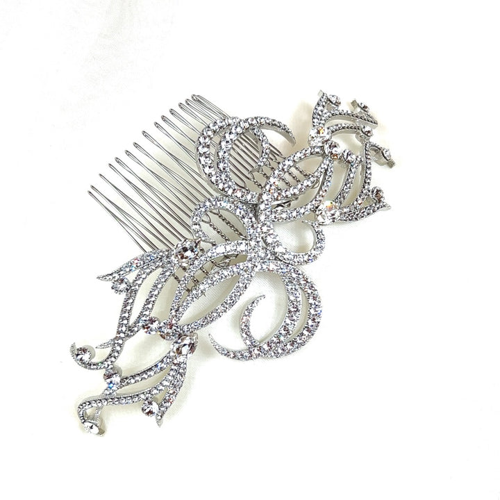 The Elegant Crystal Swirl Comb (style no. 242634) showcases luxurious silver swirls of Swarovski crystals, offering a luxurious floral and leaf design. It's displayed against a plain white background.
