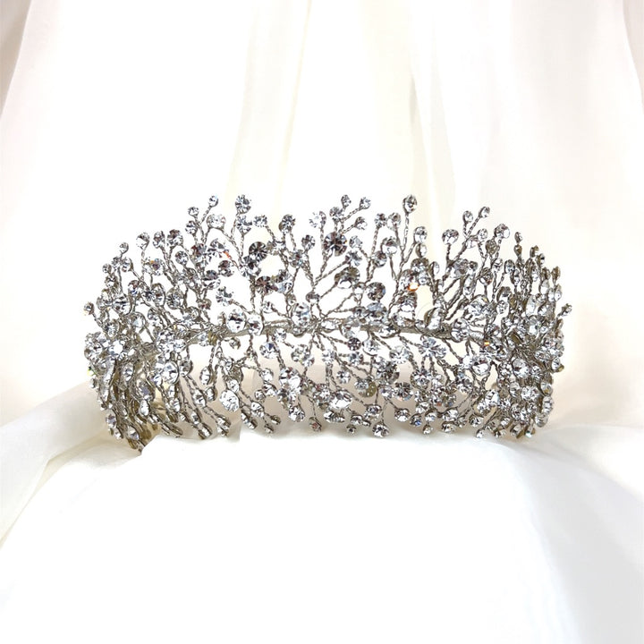 The Bursting Swarovski Crystal Headband (style no. 3910361) is an ornate and bold Swarovski crystal headband designed in a delicate pattern resembling branches. It is beautifully displayed against a soft white fabric background.