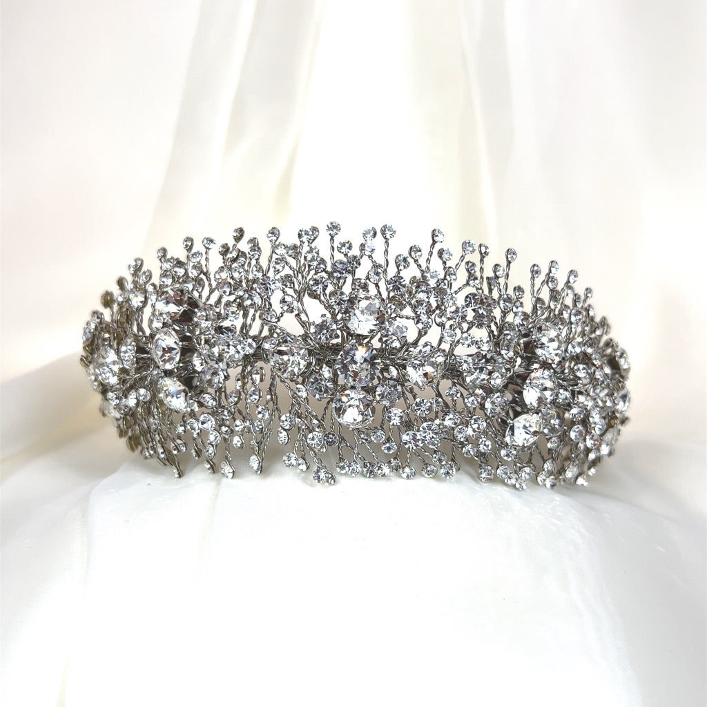 The Bold and Beautiful Swarovski Crystal Headband (style no. 391022) features a design with intricate, branch-like patterns against a delicate white fabric, embellished with numerous glittering gemstones.