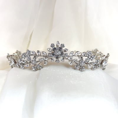 silver bridal tiara with crystal flower at its center and smaller crystal leaves and floral details
