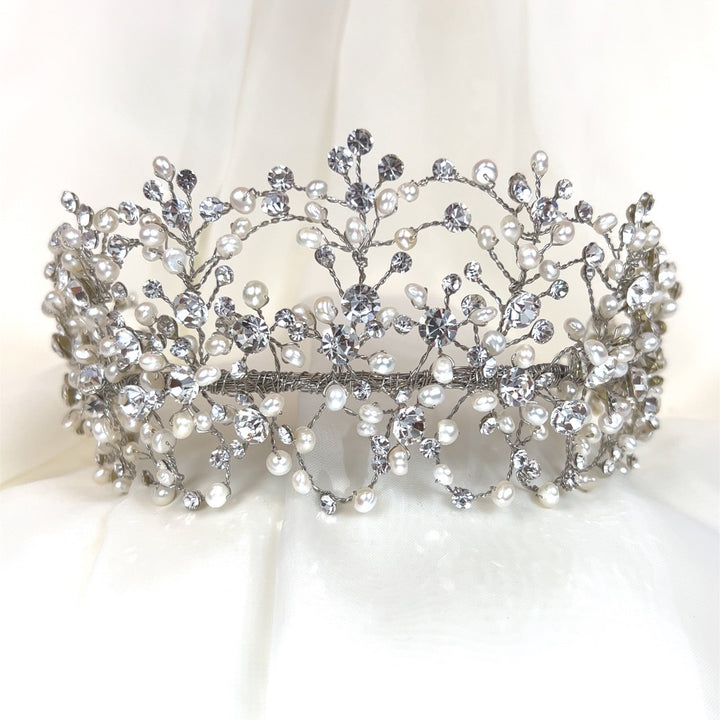 The Classy Bridal Headband style no. 242676 showcases an ornate design with intricate silver branches, pearls, and sparkling Swarovski crystals, set against a soft white background.