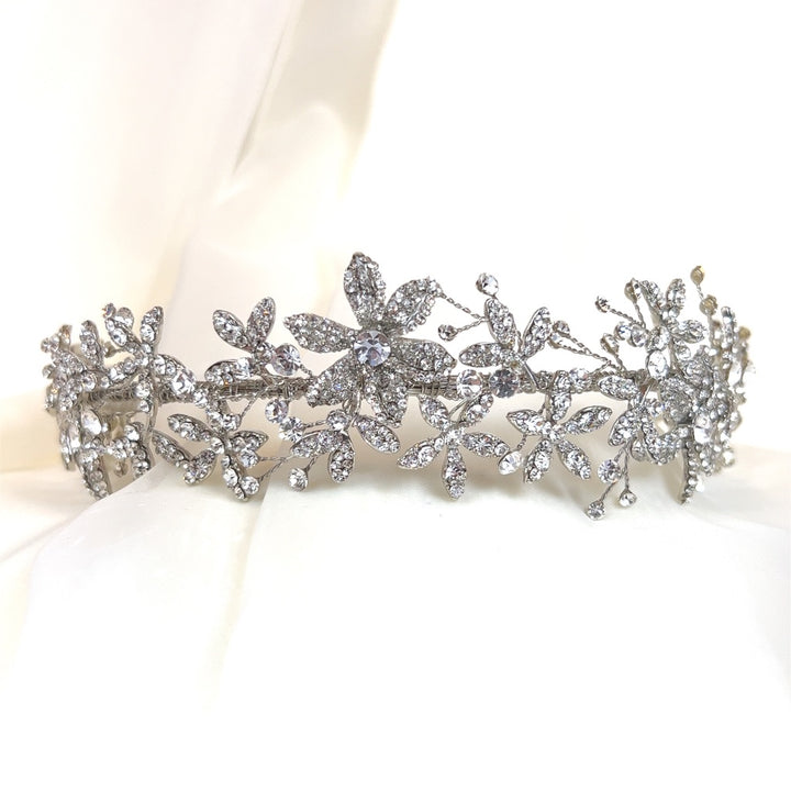 The Romantic Floral Headband (style no. 242690), with its elegant design and intricate floral and leaf patterns embellished with shimmering Swarovski crystals, evokes sophistication and elegance. 