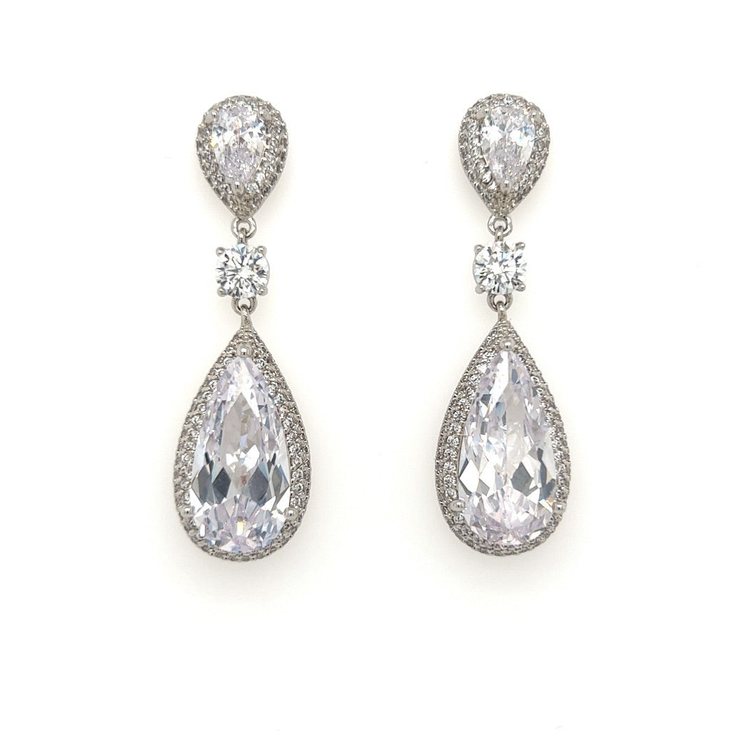 The Classical Drop Earrings, style no. E168, feature pear-shaped and round clear gemstones set in a silver-tone metal. Ideal with a Swarovski bridal tiara, the larger teardrop stones dangle below smaller round ones, all surrounded by a halo of sparkling stones on a white background.
