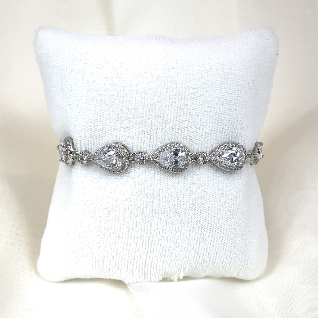 The Classic Teardrop Wedding Bracelet (style no. B142) features teardrop-shaped clear CZ gemstones and is displayed on a white cushioned stand.