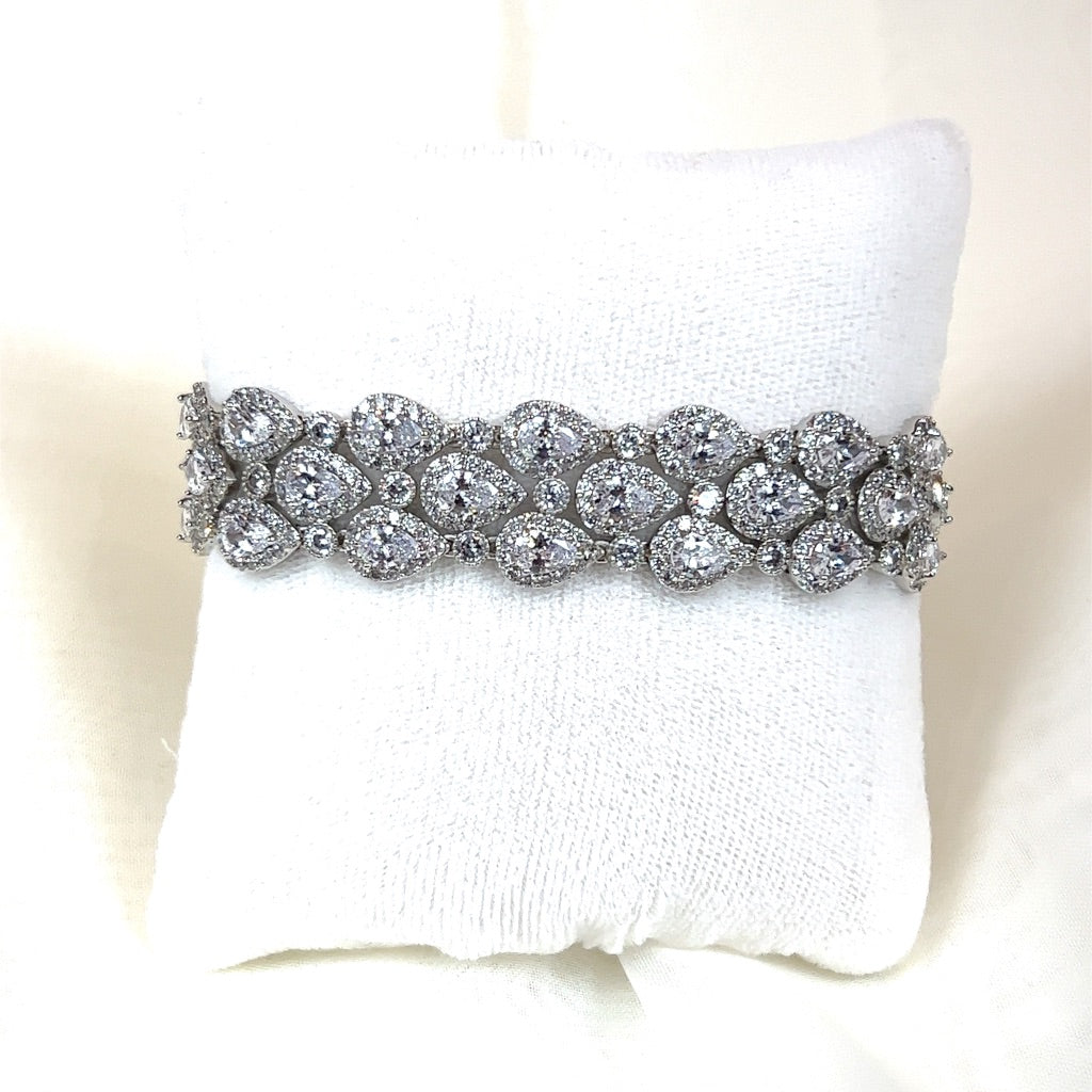 The Classic Triple Teardrop Wedding Bracelet (style no. B143) features an intricate oval and teardrop design with small CZ diamonds on a white cushioned background.