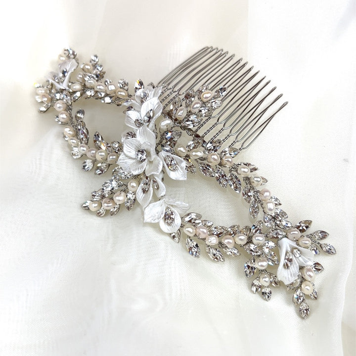 The Dazzling Pearl and Flower Hair Comb (style no. 242734), with its intricate floral design, adorned with pearls and Swarovski crystals, rests elegantly on sheer white fabric. 