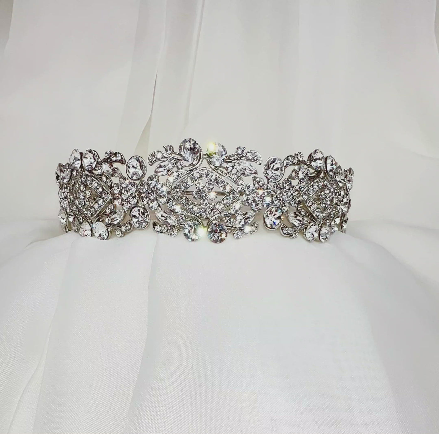 silver bridal headband with swirling floral detailing and varying sizes of round, sparkling crystals
